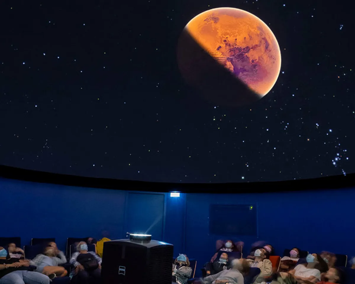 Des personnes observent le ciel depuis les sièges du Planétarium des Etincelles