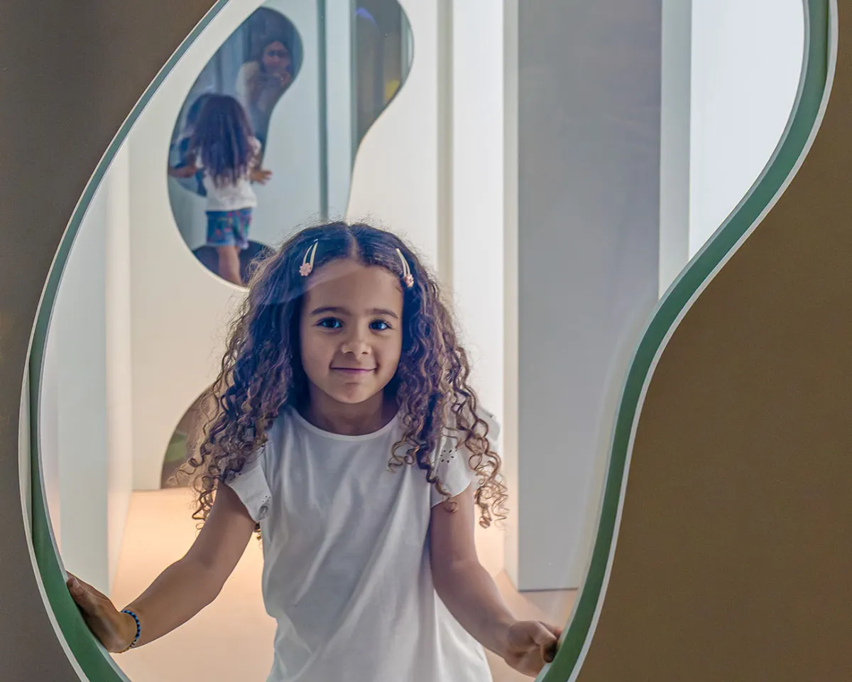 Jeune fille derrière une vitre du Palais des glaces dans l'exposition Transparence