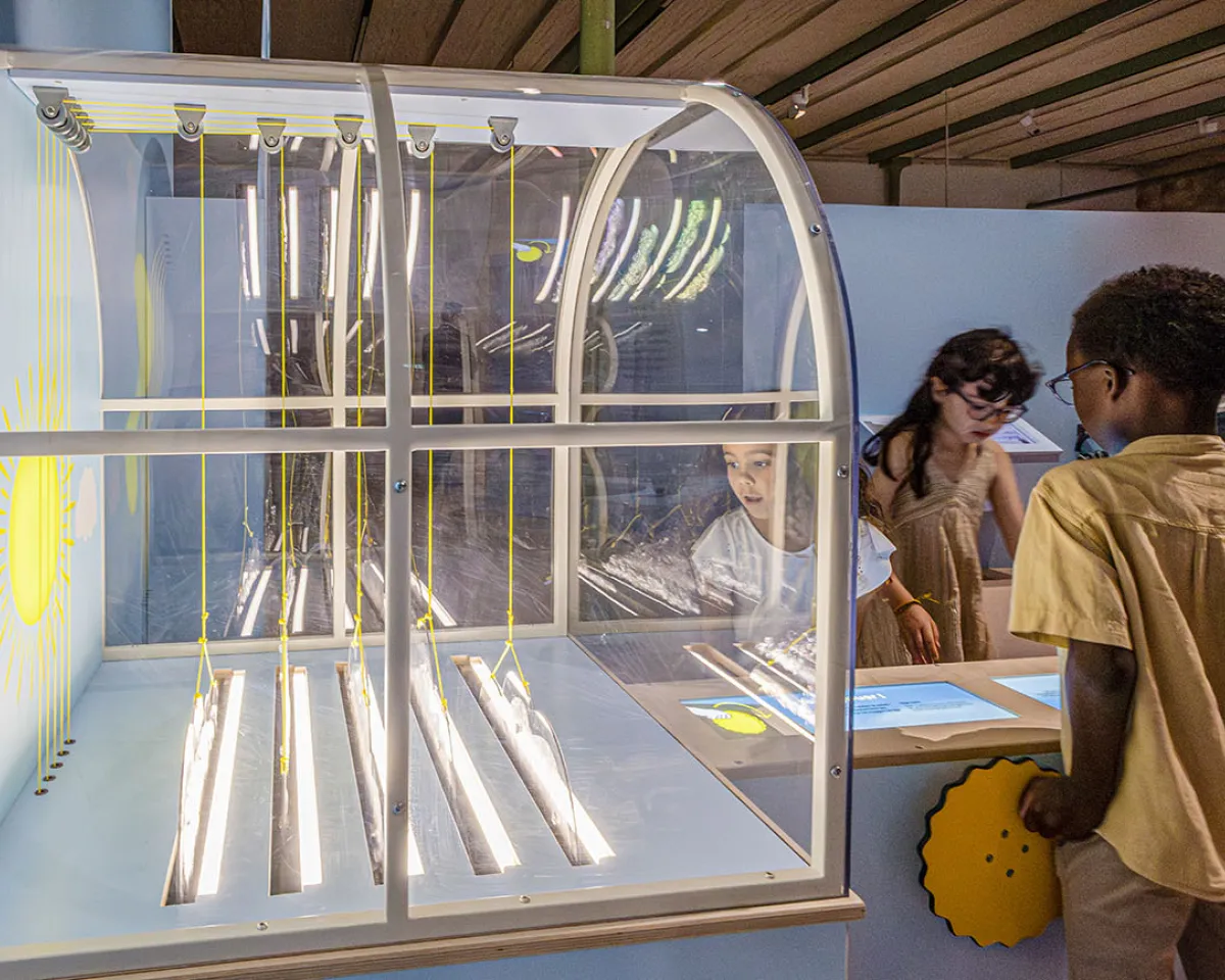 Enfants manipulant le dispositif "Cache-cache nuages" dans la partie "Le ciel" de l'exposition Transparence