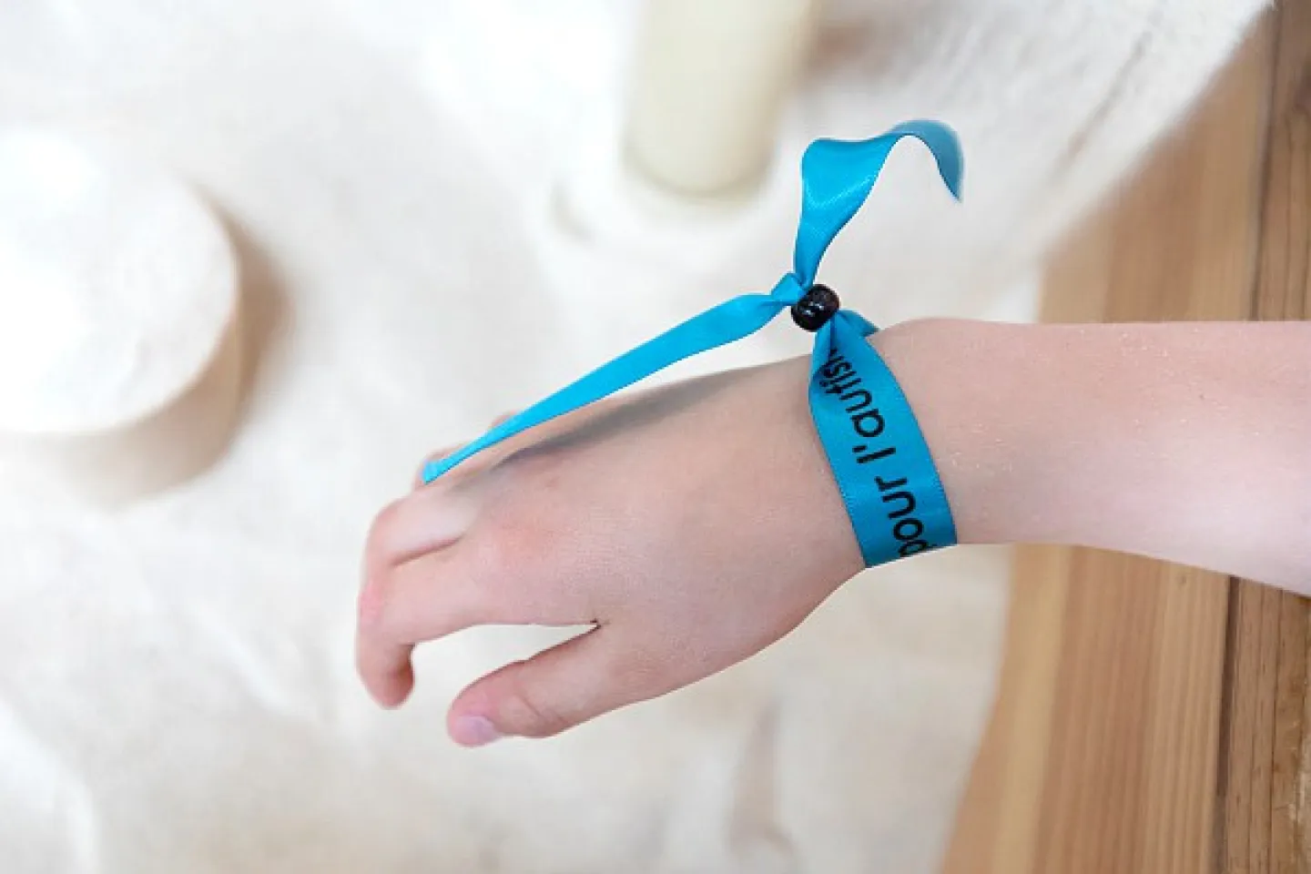 Main d'enfant avec bracelet bleu "journée de l'autisme" autour du poignet