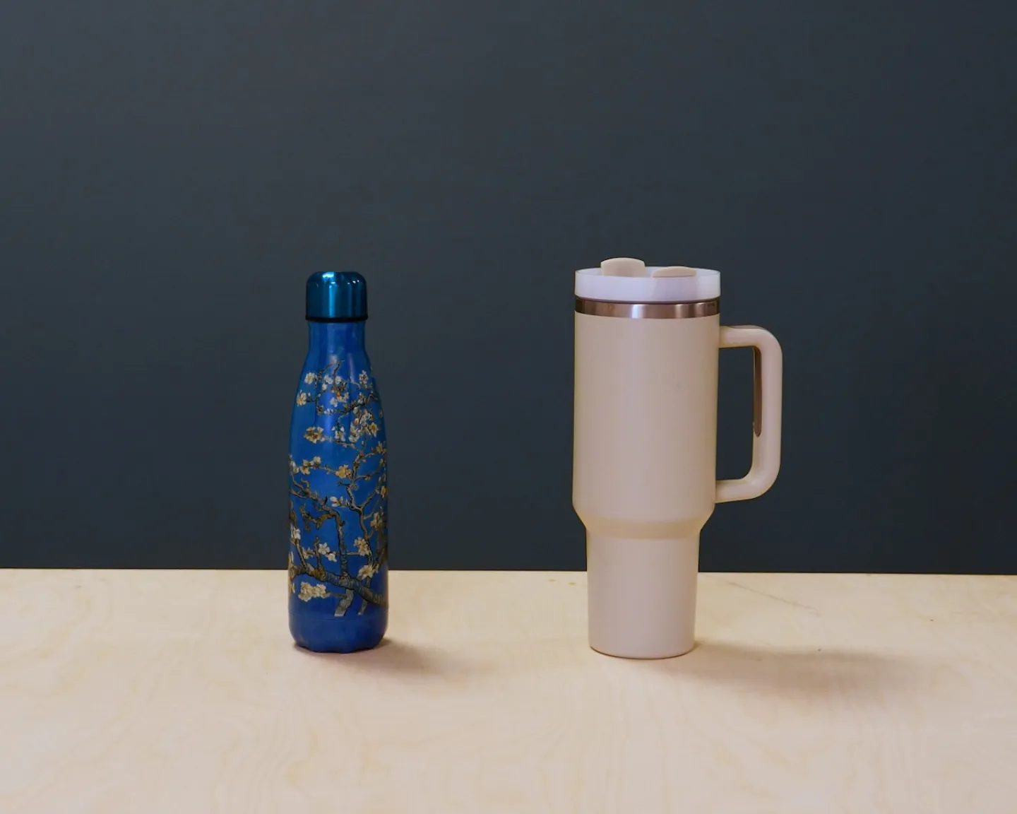 Une jolie gourde à fleurs et un mug isotherme sont posés côte à côte